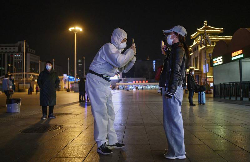 A Chinese man wearing a protective suit takes a photo of a traveller's documents  as they arrive at Beijing Railway Station in Beijing, China. Getty Images