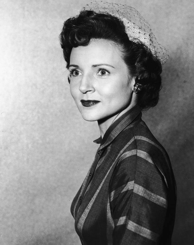 Betty White, in a veiled hat and striped dress, poses for a headshot in 1955. Getty Images