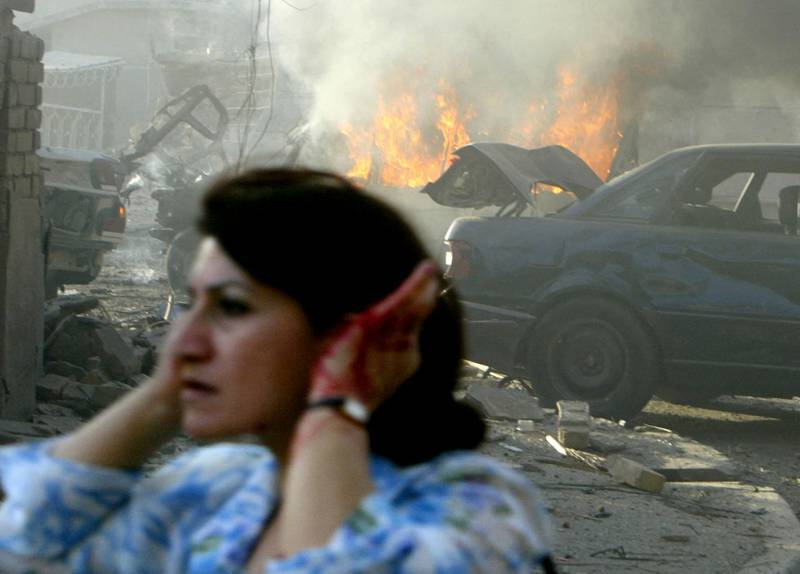 An injured Iraqi woman flees the site of two car bombs that exploded in quick succession near two Baghdad churches in August 2004. AFP
