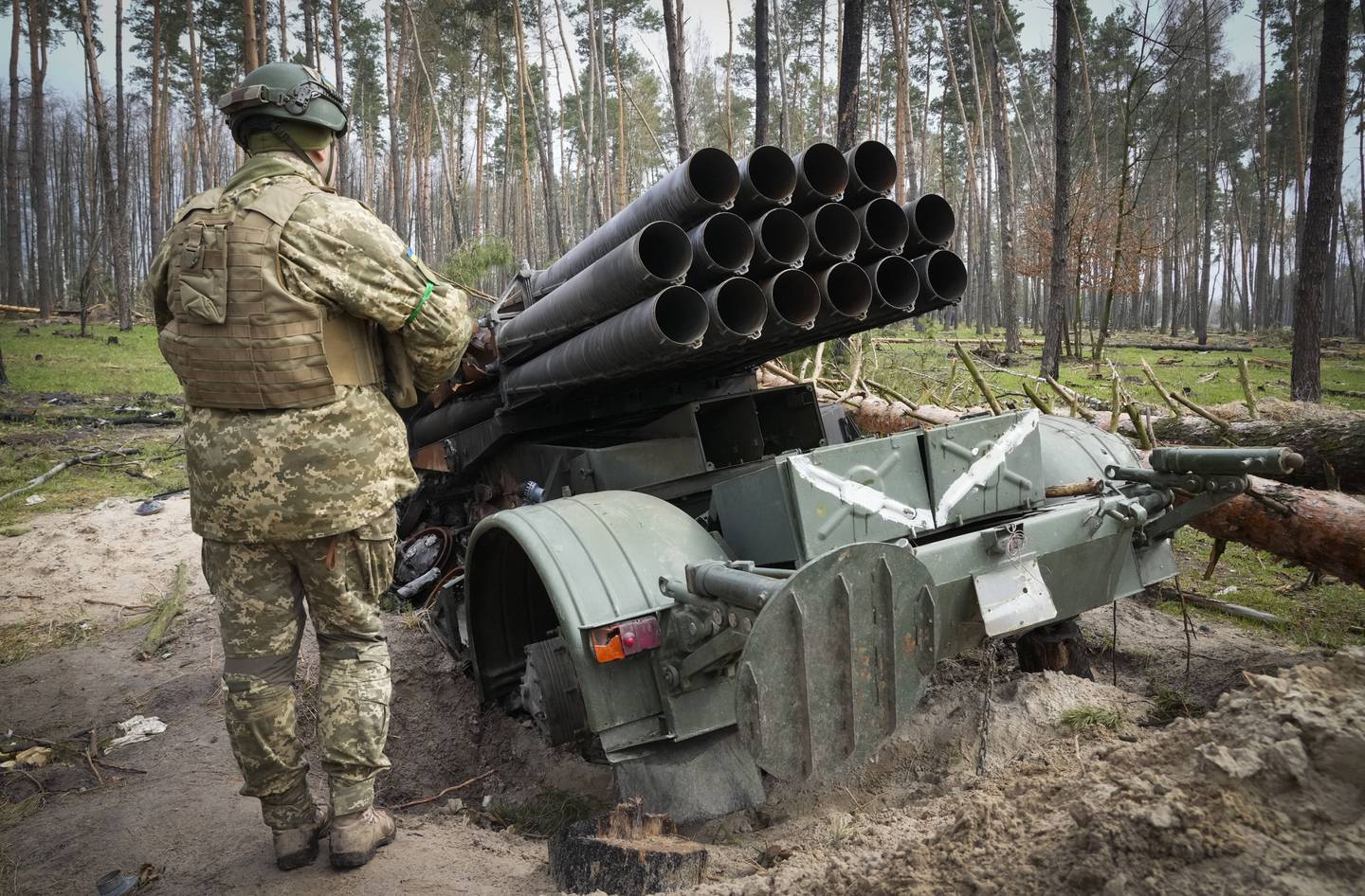 A Ukrainian soldier examines Russian multiple missiles system abandoned by Russian troops in the village of Berezivka, Ukraine, Thursday, April 21, 2022.  Writing on the missiles reads "Russian republic of Buryatiya, Kyakhta".  (AP Photo / Efrem Lukatsky)