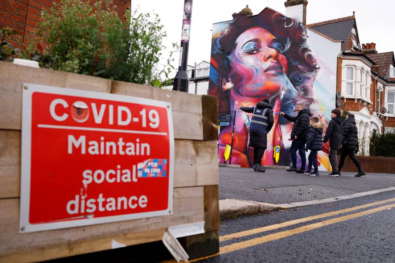 Fans outside Selhurst Park before the Premier League match between Crystal Palace and Everton pass a sign reminding them to socially distance, in south London. Reuters