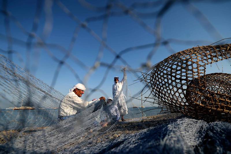 Emirati fishermen viewed through the mesh of a fishing net, at Dalma island. AFP
