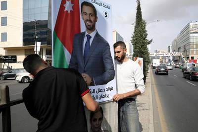 Men hang a poster of one of the candidates, ahead of parliamentary elections which will be held on November 10, amid fears over rising number of the coronavirus disease cases, in Amman. Reuters