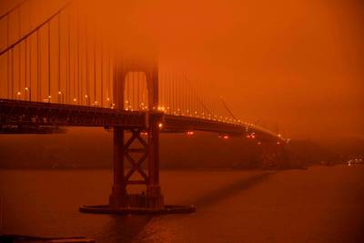 Cars drive along the Golden Gate Bridge under an orange smoke filled sky at midday in San Francisco, California on September 9, 2020. AFP