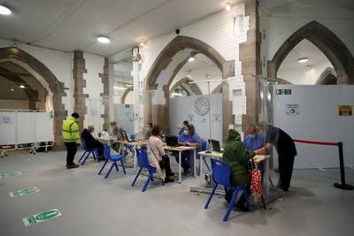 People sit and talk to healthcare workers as they wait to receive the coronavirus disease vaccine at a vaccination centre inside Blackburn Cathedral. Reuters