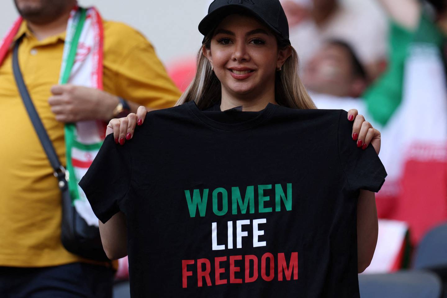 A woman holds a t-shirt with a slogan that reads 'Woman life freedom' during a football match at the Qatar World Cup. AFP