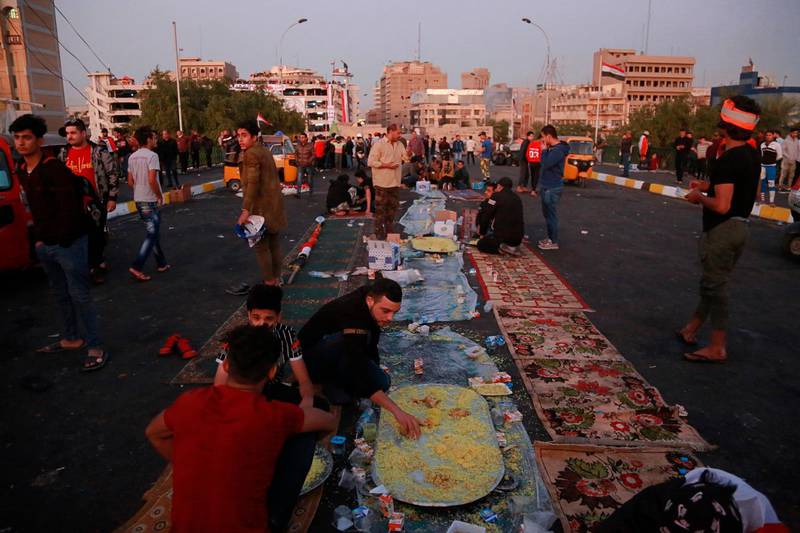 Protesters eat donated food during ongoing anti-government protests in Baghdad. AP