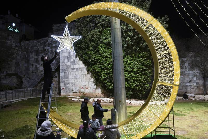 Palestinians add the final touches to a crescent moon and star decoration in preparation for Ramadan, just outside Jerusalem's Old City. AP