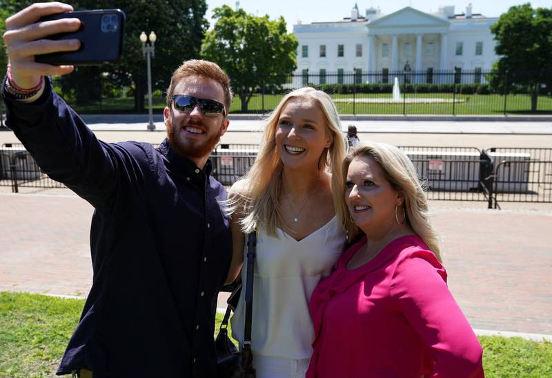 Jennifer & Abigail Lyle and John Taylor, from North carolina, pose for a selfie in Lafayette Square following its reopening near the White House in Washington, U.S., May 10, 2021. REUTERS/Kevin Lamarque