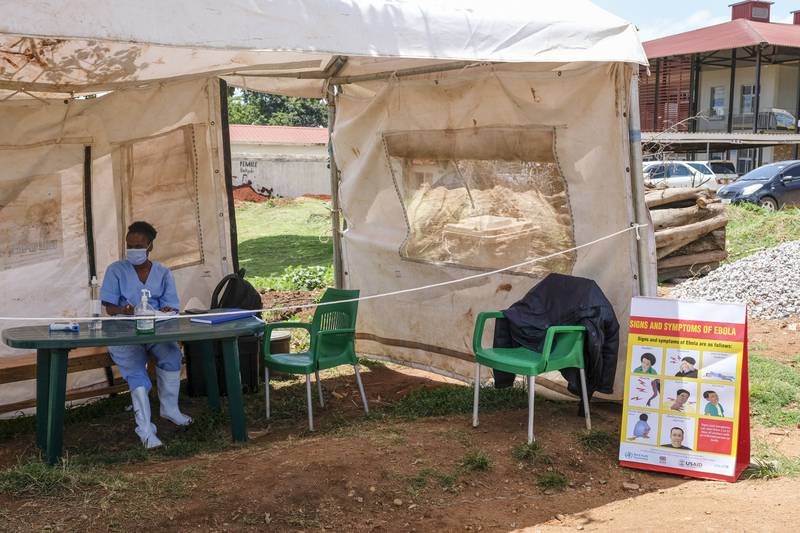 A medical attendant near a sign explaining to patients about the symptoms of Ebola at the entrance to Mubende Regional Referral Hospital. AP