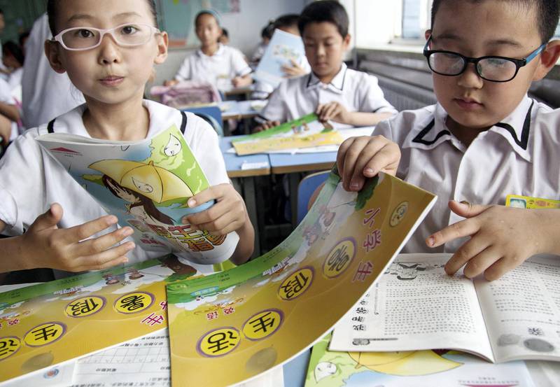 --FILE--Young near-sighted Chinese students wearing glasses receive textbooks in the classroom at a primary school ahead of the summer vacation in Boxing county, Binzhou city, east China's Shandong province, 3 July 2014.

The number of Chinese wearing glasses is rising. Most new adoptees are children. In 1970 fewer than a third of 16- to 18-year-olds were deemed to be short-sighted (meaning that distant objects are blurred). Now nearly four-fifths are, and even more in some urban areas. A fifth of these have "high" myopia, that is, anything beyond 16 centimetres is unclear. The fastest increase is among primary school children, over 40% of whom are short-sighted, double the rate in 2000. That compares with less than 10% of this age group in America or Germany. The incidence of myopia is high across East Asia, afflicting 80-90% of urban 18-year-olds in Singapore, South Korea and Taiwan. The problem is social rather than genetic. A 2012 study of 15,000 children in the Beijing area found that poor sight was significantly associated with more time spent studying, reading or using electronic devices, along with less time spent outdoors. The biggest factor in short-sightedness is a lack of time spent outdoors. Exposure to daylight helps the retina to release a chemical that slows down an increase in the eye's axial length, which is what most often causes myopia. Schoolchildren in China are often made to take a nap after lunch rather than play outside; they then go home to do far more homework than anywhere outside East Asia. The older children in China are, the more they stay indoors, and not because of the country's notorious pollution.