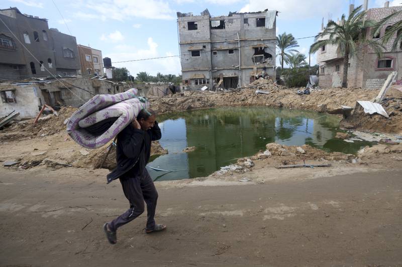 A Palestinian man walks by buildings destroyed in the Israeli bombardment of the Gaza Strip. AP