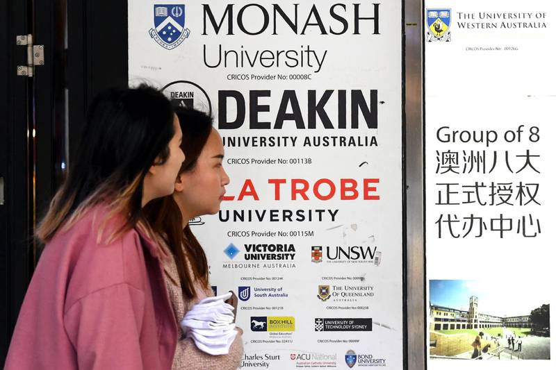 People walk past signage for Australian universities in Melbourne's central business district on June 10, 2020, as Australian officials and leading universities rejected China's claims students should be "cautious" in choosing to study Down Under because of concerns over racist incidents during the coronavirus pandemic. China's Ministry of Education told students on June 9 there had been "multiple discriminatory incidents against Asians in Australia" during the pandemic, ramping up diplomatic tensions between the two countries. / AFP / William WEST
