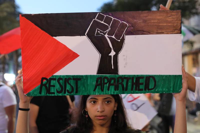 A woman holds up a sign with the Palestinian flag, a Black Power fist and the slogan 'Resist Apartheid' as Jewish and Arab Israelis protest against US President Donald Trump's 'peace plan' for the Middle East as they march in Tel Aviv, Israel, in June 2020.  EPA