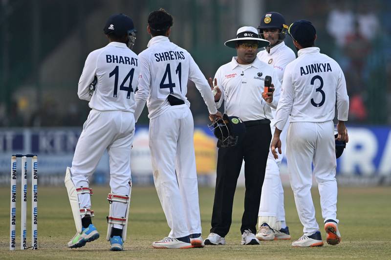 Field umpire (C) speaks with India's players on the fifth and final day of the first Test cricket match between India and New Zealand at the Green Park Stadium in Kanpur on November 29, 2021.  (Photo by Sajjad HUSSAIN  /  AFP)  /  IMAGE RESTRICTED TO EDITORIAL USE - STRICTLY NO COMMERCIAL USE