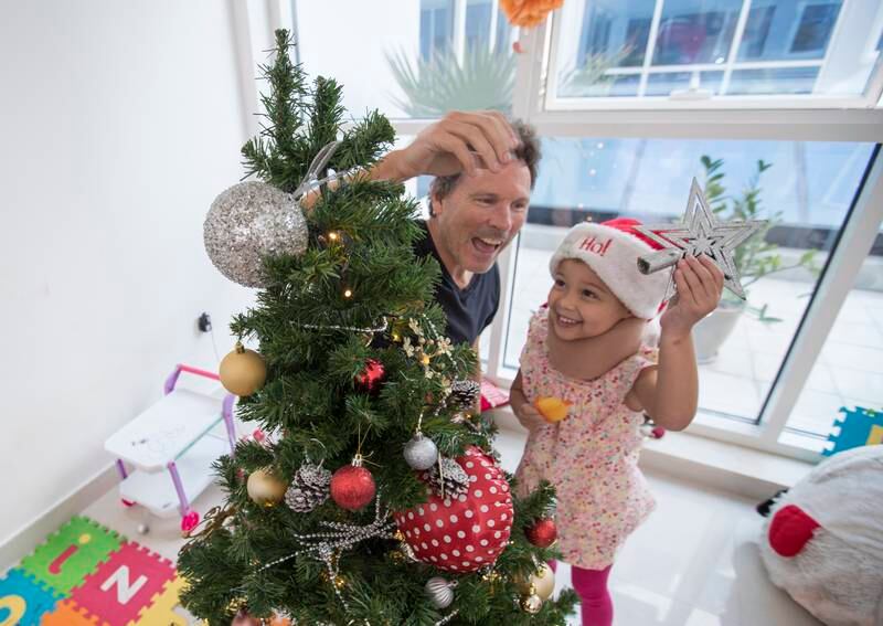 Alex Broun with his daughter Naraya decorate a Christmas tree at their home.