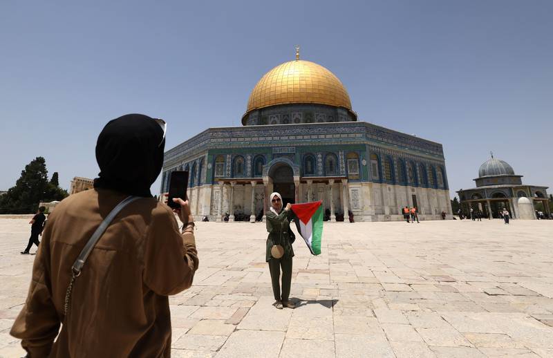 A girl poses for a picture with the Palestinian flag in front of the Dome of the Rock mosque inside Jerusalem's Al Aqsa Mosque complex, on May 27. AFP