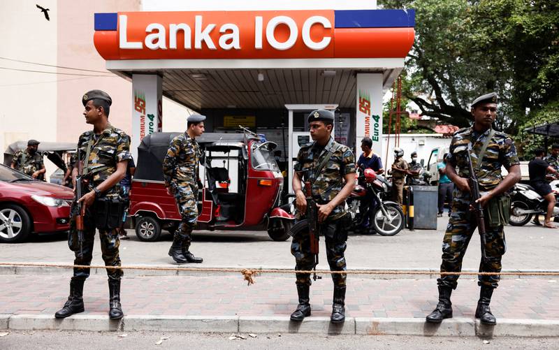 Air Force members stand guard at a petrol station in Sri Lanka as people queue to buy fuel. Reuters