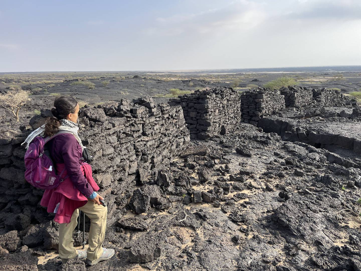 Reem Philby crosses the dark rock of the Harrat lava field