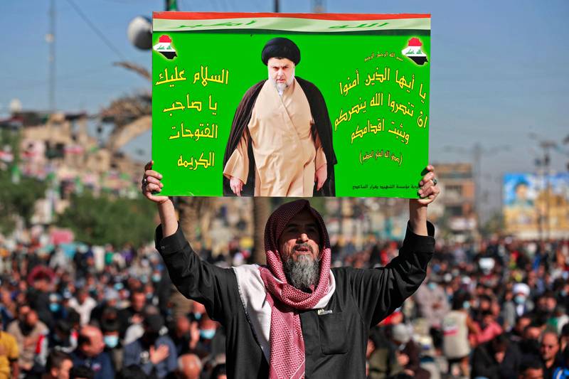 An Iraqi man holds a picture of Moqtada Al Sadr during Friday prayers in Baghdad's Sadr City district. AFP