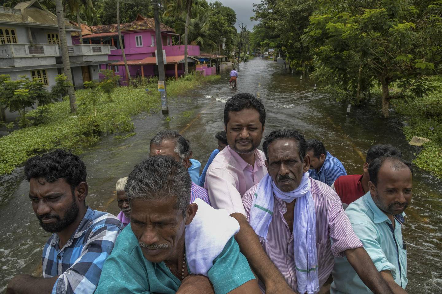 KERALA, INDIA - AUGUST 20: Locals cross the flood water after taking the lift on the rescue truck on August 20, 2018 in Chengannur, India. Over 350 people have reportedly died in the southern Indian state of Kerala after weeks of monsoon rains which caused the worst flooding in nearly a century. Officials said more than 800,000 people have been displaced and taken shelter in around 4,000 relief camps across Kerala as the Indian armed forces step up efforts to rescue thousands of stranded people and get relief supplies to isolated areas.  (Atul Loke/Getty Images)