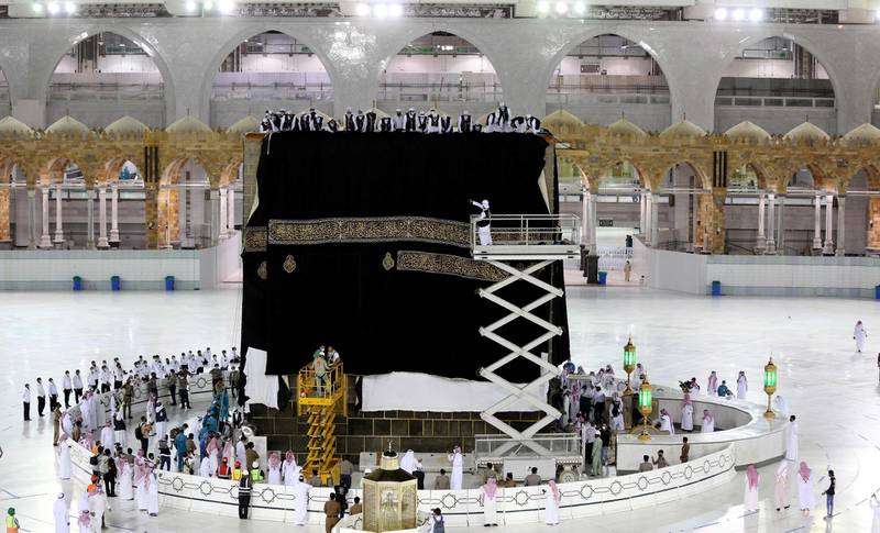Saudi labourers put the new Kiswa, the protective cover that engulfs the Kaaba, made from black silk and gold thread and embroidered with Koran verses in Saudi Arabia's holy city of Mecca. AFP