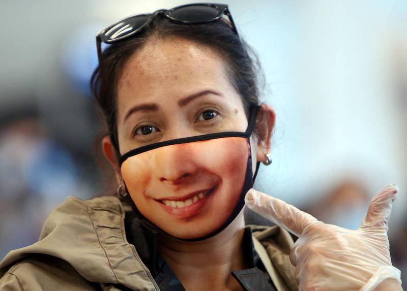A woman displays her mask as Filipinos who availed general amnesty granted by the Kuwaiti government gather at the Kuwait International Airport Terminal on their home to Manila amid the coronavirus COVID-19 pandemic crisis. For systematic documentations, illegal ex-pats from the Philippines, Egypt, India, Bangladesh, Sri Lanka and other countries were at first, requested to submit themselves at a school compound in Farwaniya arranged according to nationalities. AFP