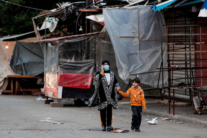 A mask-clad woman and boy walk past shuttered shops and stalls in Souk Sabra in the southern suburbs of the Lebanon's capital Beirut, despite a national total lockdown as a measure against the COVID-19 coronavirus pandemic. AFP