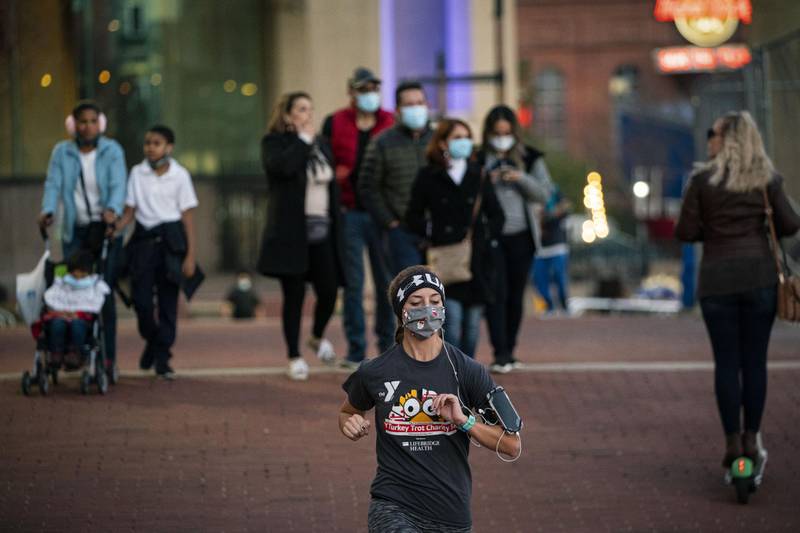 People wearing protective masks pass through Inner Harbor in Baltimore, Maryland, US. Coronavirus infections continue to rise in the greater Washington region, with more than 5,000 new cases reported on Thursday, a daily record. Bloomberg
