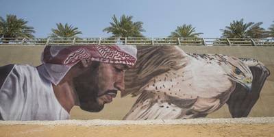 An Emirati with his falcon is one of a series of images of the UAE that forms part of a 600-metre mural at Al Raha Beach, completed by Elio Mercado and his team of artists from Miami. Aldar properties unveiled the artwork this month. Mona Al Marzooqi / The National 