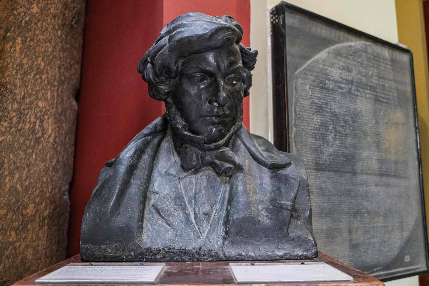 A bust of French scholar and philologist Jean-Francois Champollion, and behind, a replica of the Rosetta Stone on display at the entrance of the Egyptian Museum in Cairo. Photo: AFP