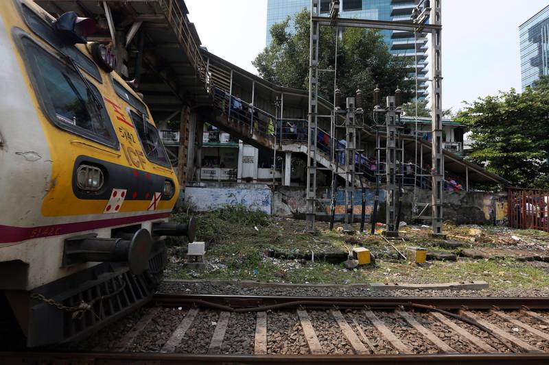 epa06233890 Commuters walk on foot overbridge as the local train passes by at Elphinston Road railway station in Mumbai, India, 29 September 2017. Reports state at least 22 people have died and around 25 have been injured in a stampede at a railway station in Mumbai. An official said that the stampede occurred when many people who had sought shelter from the rain on a bridge, which serves as a passageway to the Elphinstone Road railway station, tried to get out.  EPA/DIVYAKANT SOLANKI