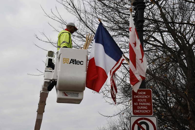 A worker hangs French, US and District of Columbia flags for the state visit. AFP