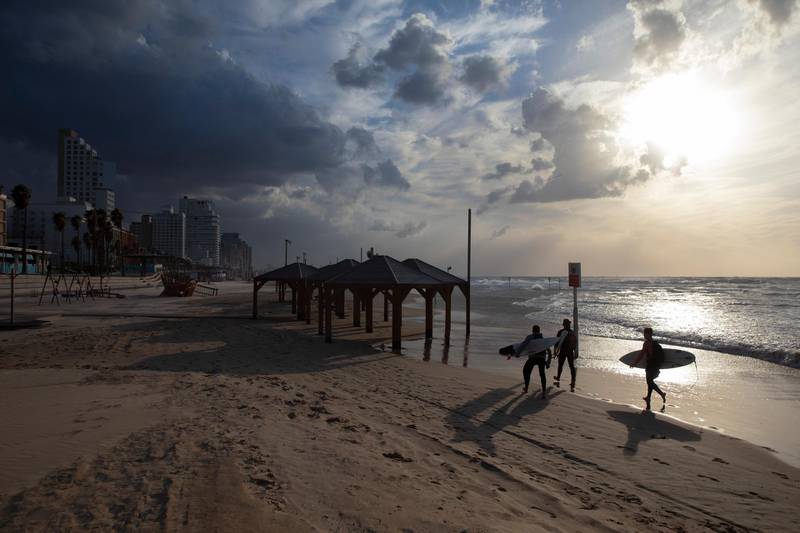 Surfers carry their boards along the beach front during a nationwide lockdown to curb the spread of the oronavirus, In Tel Aviv, Israel.  AP