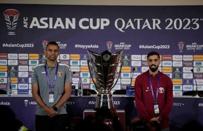 Jordan's Salem Al Ajalin, left, and Qatar's Hassan Al Haydos pose next to the Asian Cup trophy ahead of Saturday's final. AP