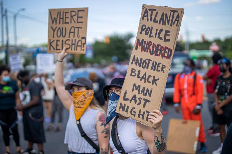 Protesters hold placards near the scene of an overnight police shooting which left a black man dead at a Wendy's restaurant in Atlanta. EPA