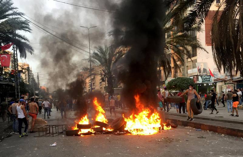 Demonstrators walk near burning tires in Tripoli, Lebanon. REUTERS