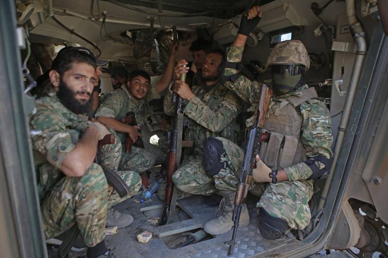 Turkish-based Syrian fighters sit inside an armoured personnel carrier near the Syrian border town of Tal Abyad, as they prepare to take part in the Turkish-led assault on northeastern Syria.  Ankara stepped up its assault on Kurdish-held border towns in northeastern Syria, defying mounting threats of international sanctions, even from Washington. AFP