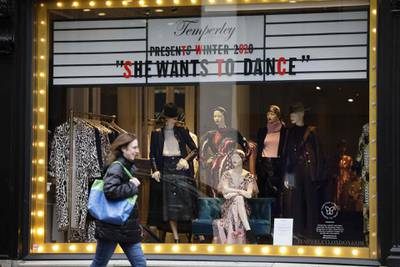 A pedestrian passes a closed shop with a window display from last year in the Mayfair area of central London. AFP