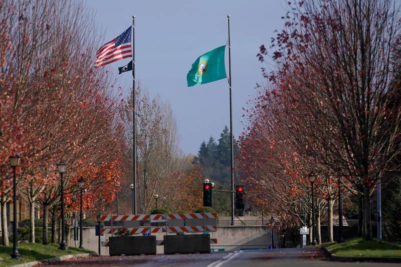 The Washington state and POW flags fly near a red traffic light and a road closed barricade, at the Capitol in Olympia, Washington. AP Photo