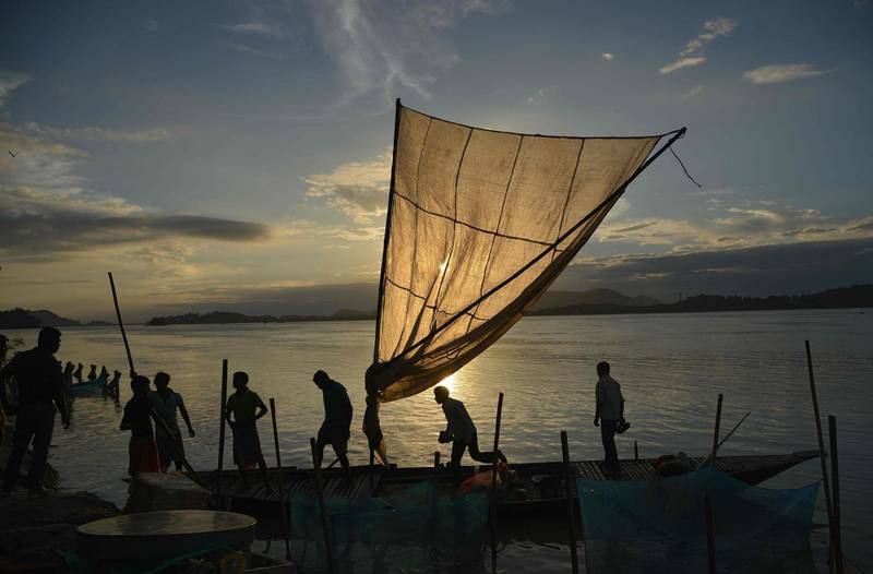 Indian fishermen load their boat with produce to sell at a market at the banks of the Brahmaputra River at Ujanbazar Ghat in Guwahati.  AFP