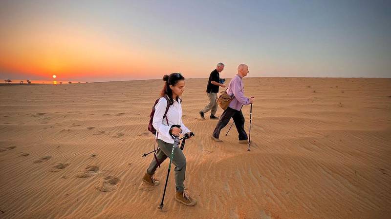 Alan Morrissey, Mark Evans and Reem Philby walk across the sand