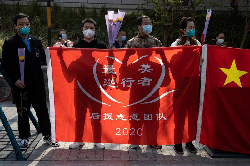 Volunteers hold a banner with the words "The most beautiful first responders" before a national moment of mourning for victims of coronavirus in Wuhan in central China's Hubei Province. AP Photo