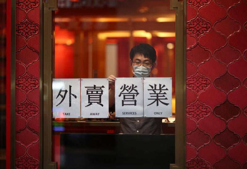 A man wearing a face mask displays a sign for takeaway services at an eatery after New South Wales began shutting down non-essential businesses and moving toward harsh penalties to enforce self-isolation as the spread of coronavirus disease reached a "critical stage" in Sydney, Australia. Reuters