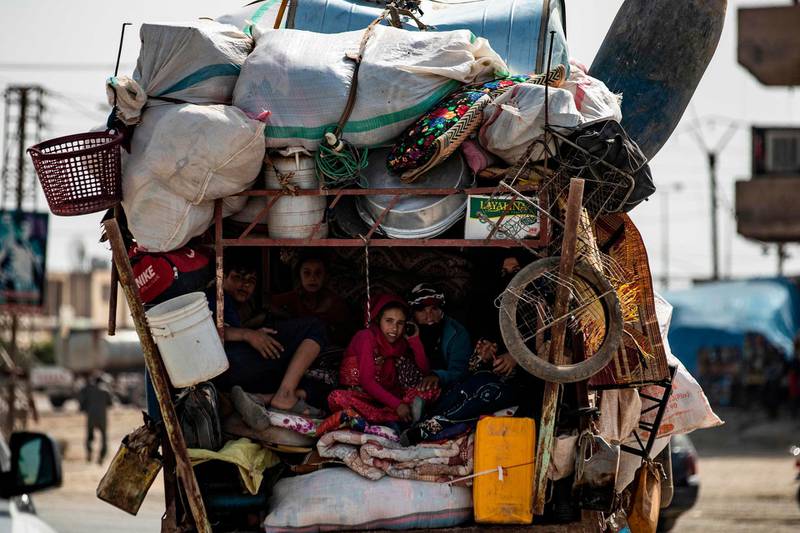 CORRECTION / TOPSHOT - Displaced Syrians sit in the back of a pick up truck as Arab and Kurdish civilians flee amid Turkey's military assault on Kurdish-controlled areas in northeastern Syria, on October 11, 2019 in the town of Tal Tamr in the countryside of Syria's northeastern Hasakeh province. Turkey pressed its deadly offensive against Kurdish targets in Syria as it battled to seize key border towns on the third day of an operation that has forced 100,000 civilians to flee. / AFP / Delil SOULEIMAN
