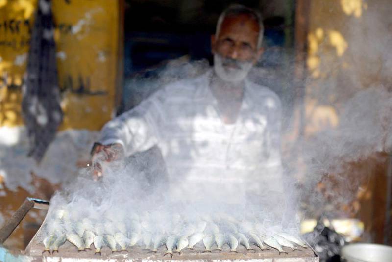 A man grills fish to sell in front of his house. Amr Abdallah Dalsh / Reuters
