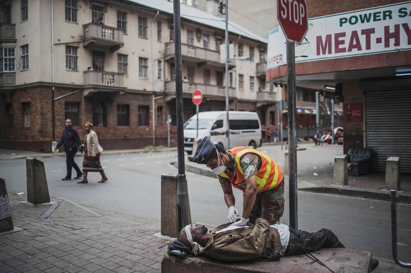 A military police officer from the South African National Defence Force (SANDF), checks on a homeless man who overdosed, while on patrol in the streets of Hillbrow, Johannesburg.  AFP