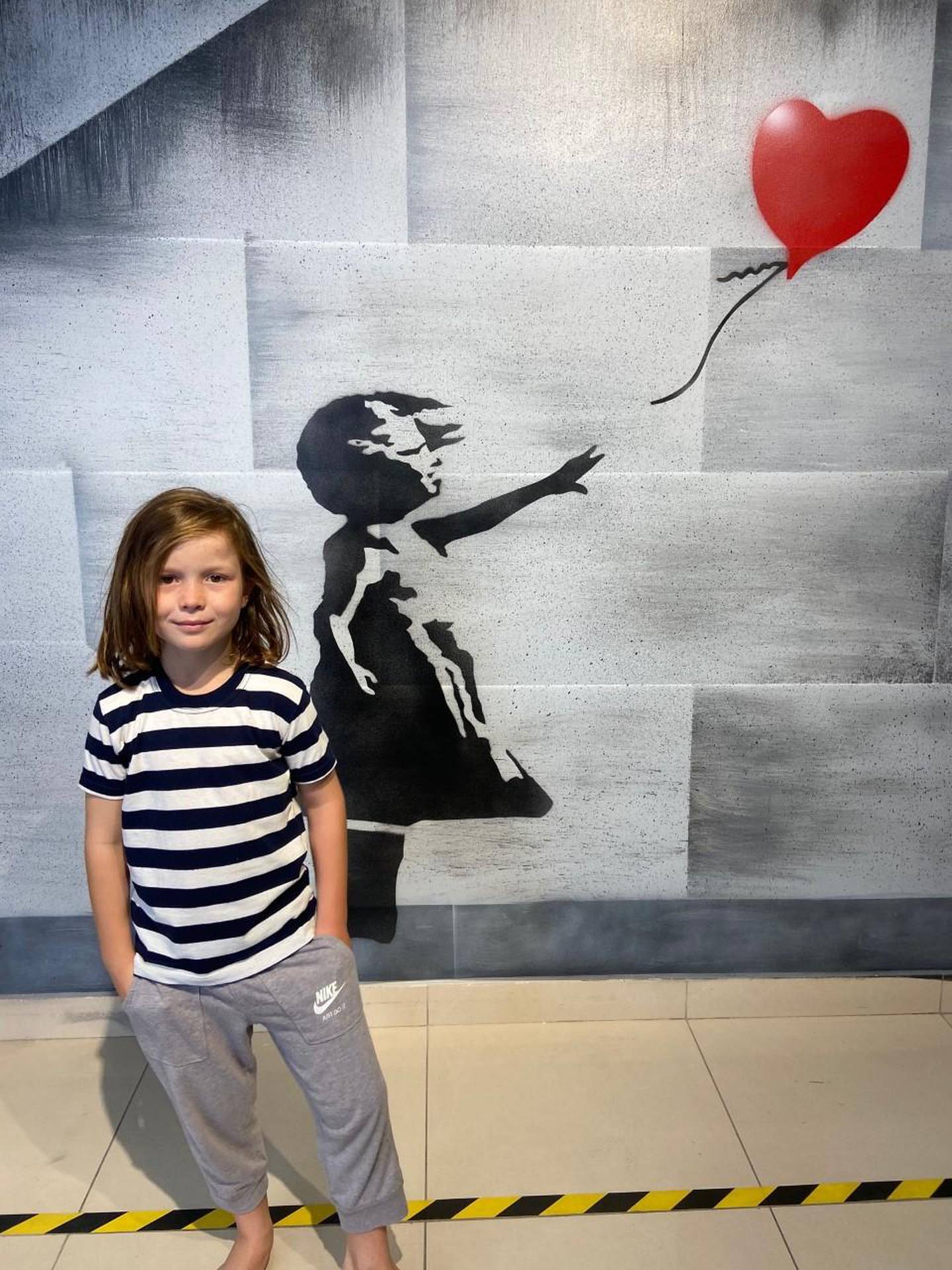 Indiana, 8, beside one of Banksy's most recognisable images: 'Girl With Balloon'. Courtesy Gemma White