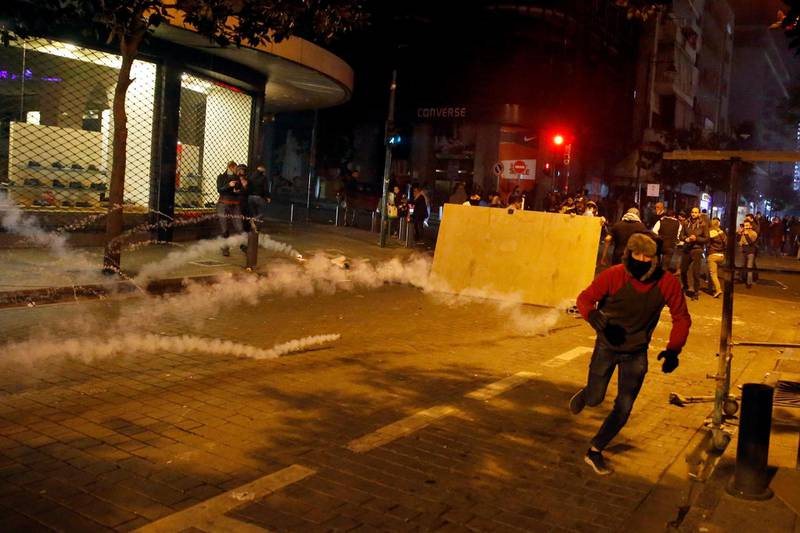 Anti-government protesters run to escape tear gas that fired by riot police, during ongoing protests against the Lebanese central bank's governor and against the deepening financial crisis, at Hamra trade street, in Beirut, Lebanon.  AP