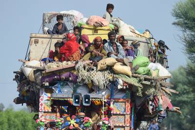 Displaced people sit on a tractor with their belongings as they make their way to higher ground in Shikarpur. AFP